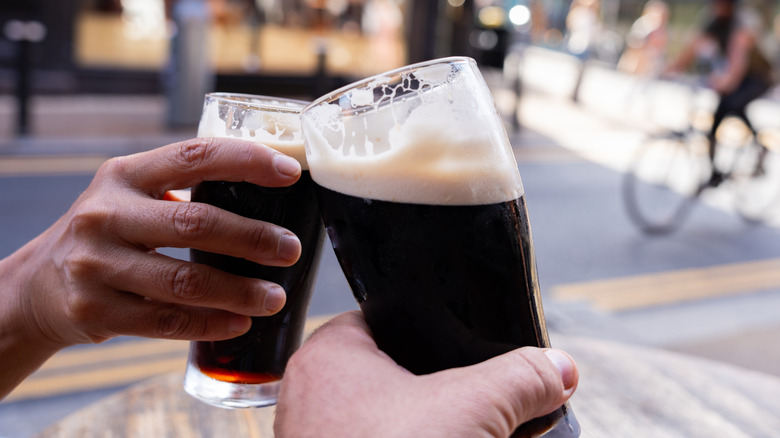 Two beers clinking outdoors on a lively street