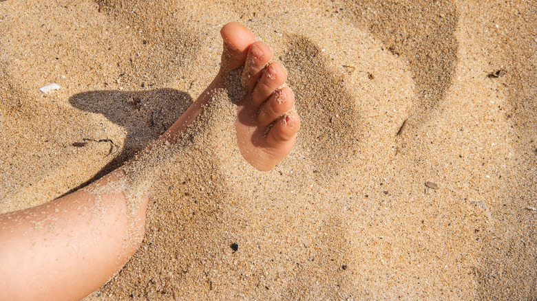 Child's foot covered in beach sand