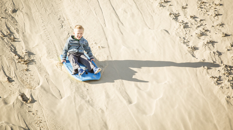 Boy sledding down a sand dune