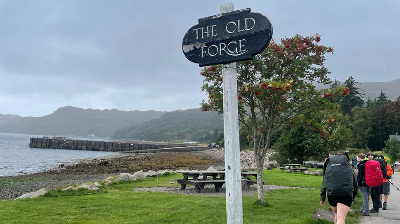 A sign reading "The Old Forge" in front of hikers