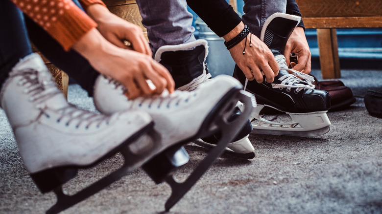 Two people lacing up ice skates