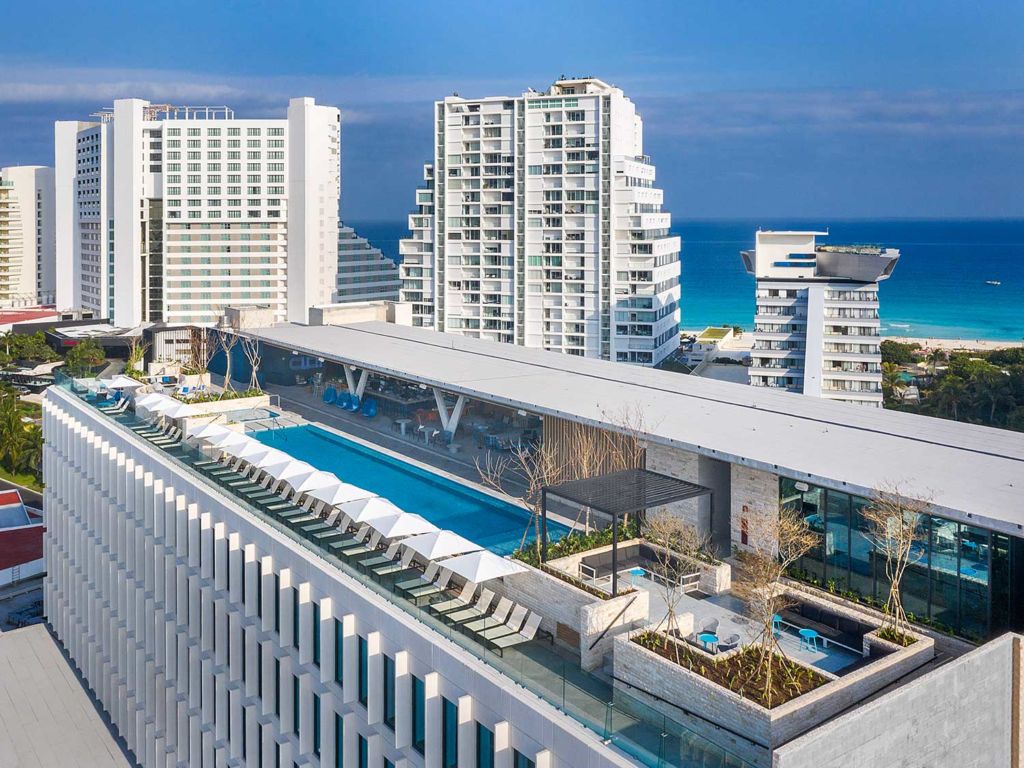 A large outdoor pool and lounge on the rooftop of a beach resort.