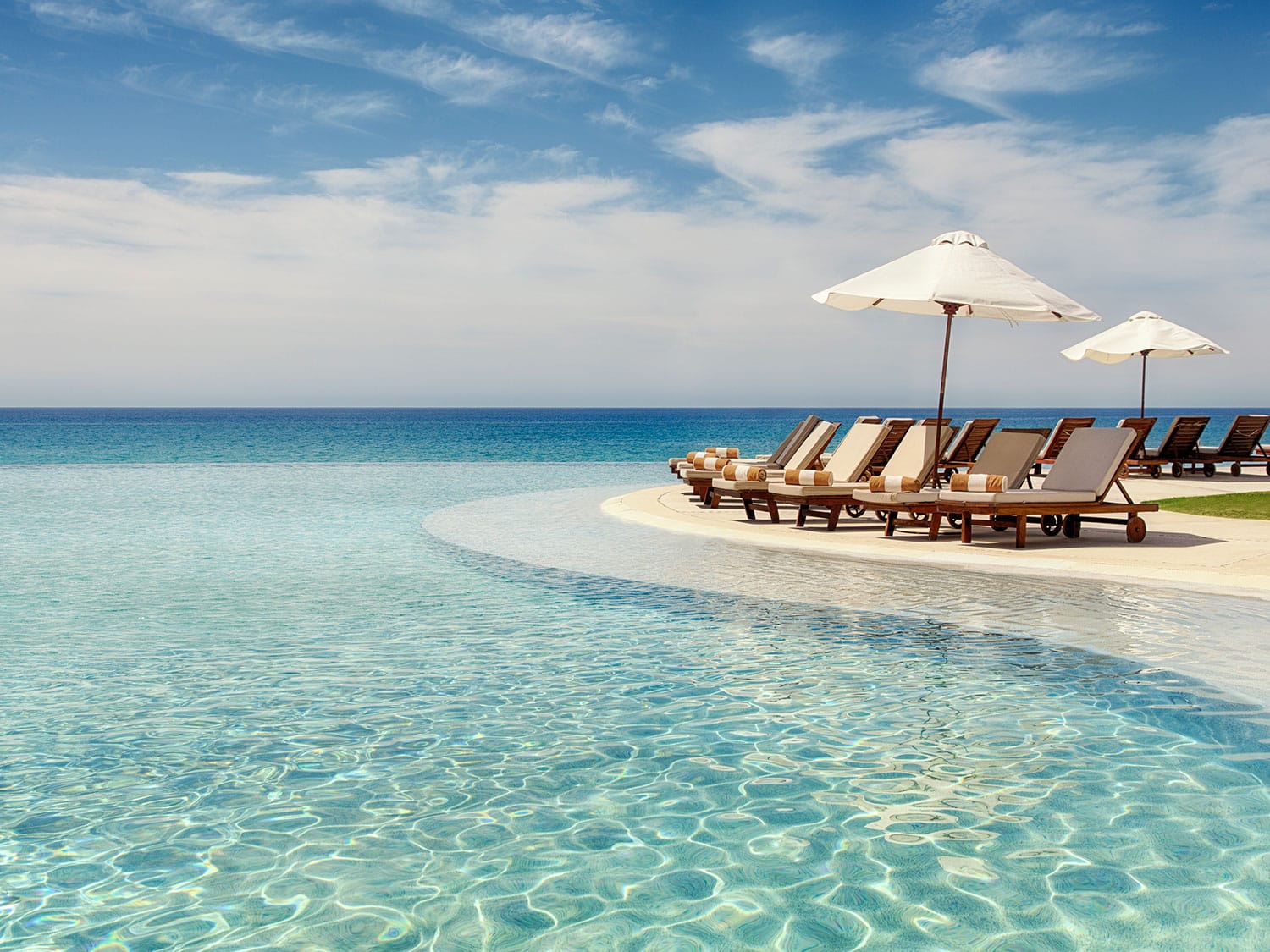 An infinity horizon pool by lounge chairs.