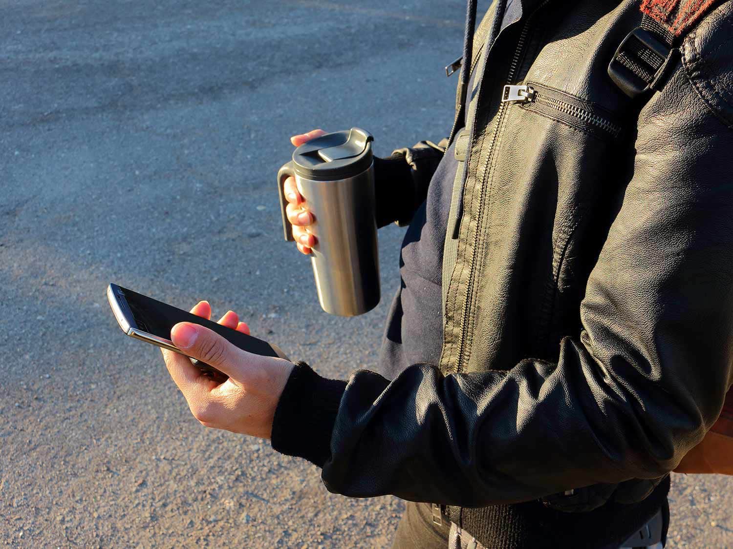 Man using a phone and travel cup.