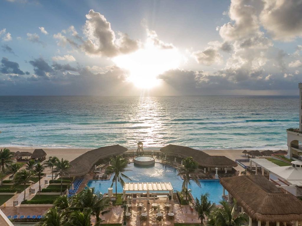 Aerial photo of the sunset against the waves of the ocean beside a beach resort.