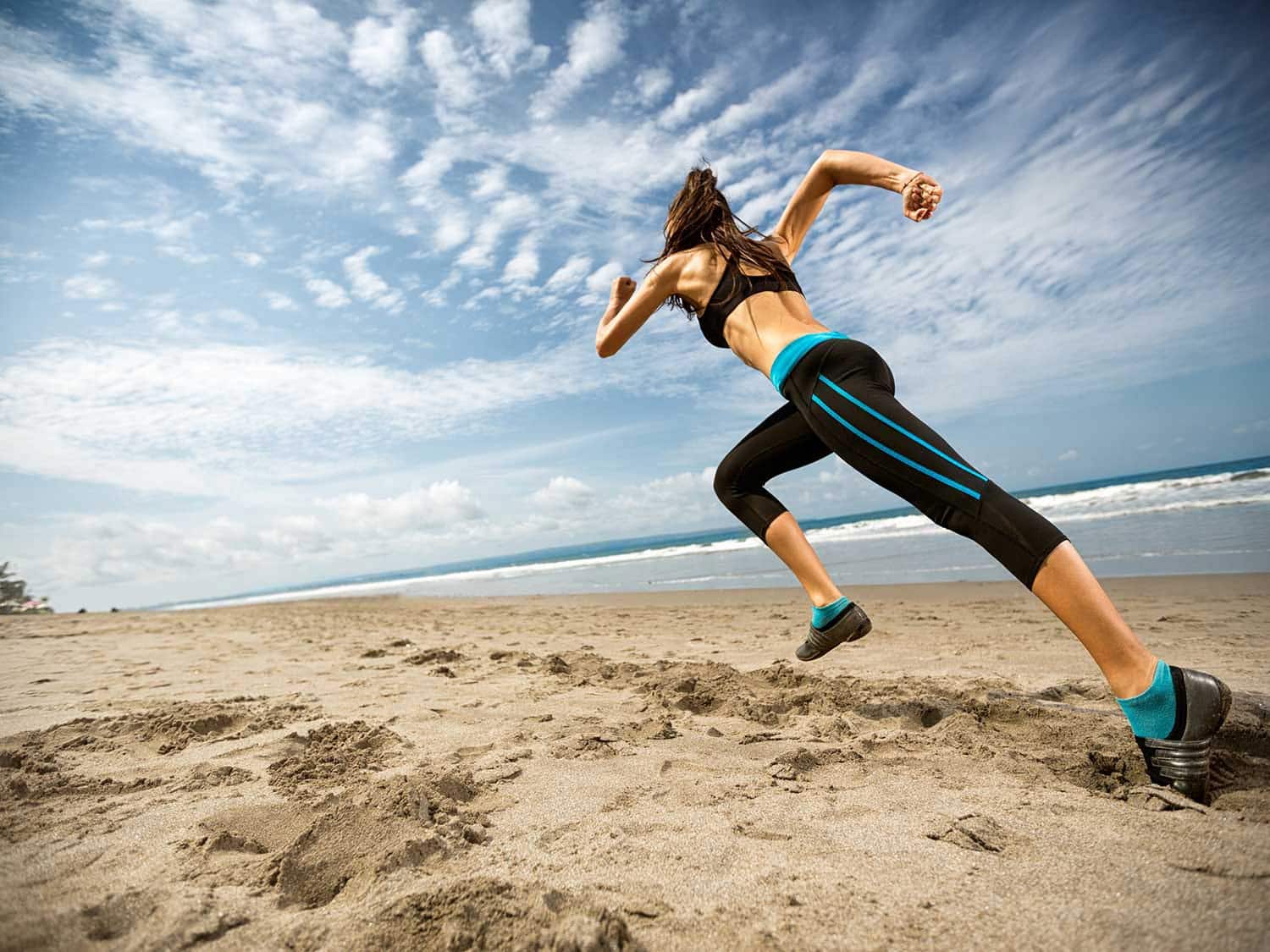 A woman  in athletic wear.runs on the beach.